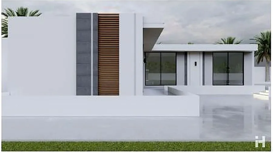 The minimal chalet in its landscape setting, palms against a white wall.